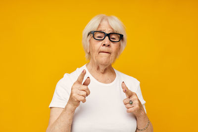 Portrait of young woman against yellow background