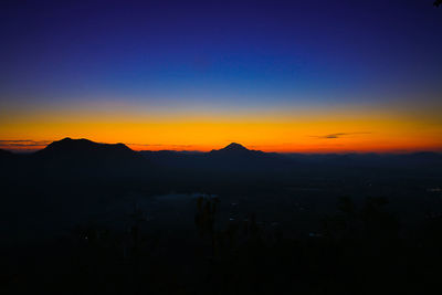 Scenic view of silhouette mountains against orange sky