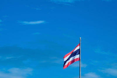 Low angle view of flag against blue sky