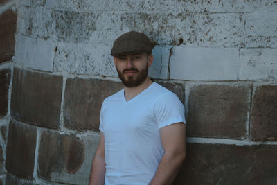 Portrait of young man standing against wall