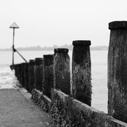 Wooden posts on beach against clear sky