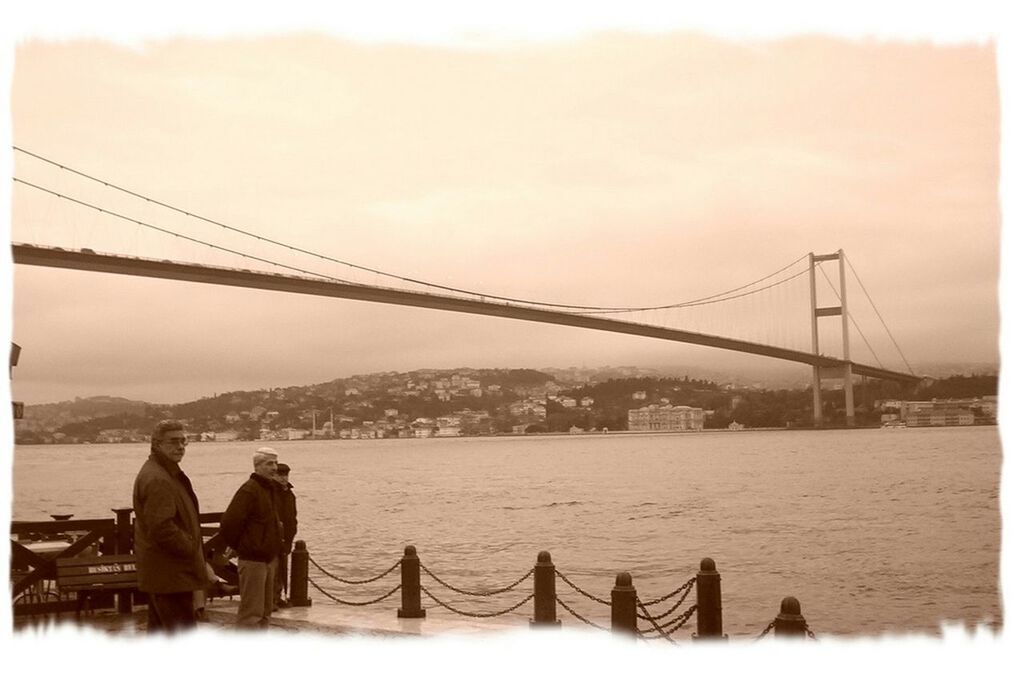 transfer print, water, connection, men, lifestyles, bridge - man made structure, leisure activity, transportation, auto post production filter, river, sky, person, suspension bridge, sea, travel, large group of people, nautical vessel, engineering, bridge