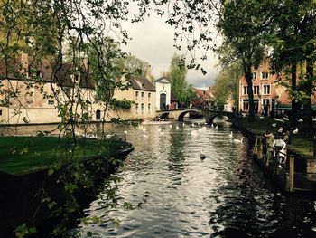 Canal in city against sky