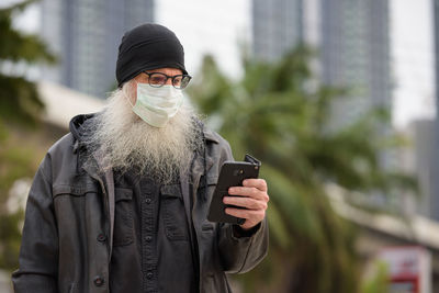 Midsection of man using mobile phone in city