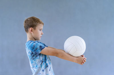 Boy playing with ball against blue sky