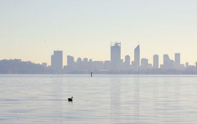 View of sea and buildings against clear sky