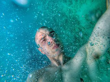 Shirtless young man swimming in sea