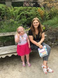 Portrait of smiling mother with daughter sitting on bench