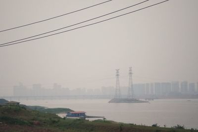 Electricity pylons in city against sky