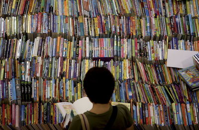 High angle view of woman holding book while standing at stall