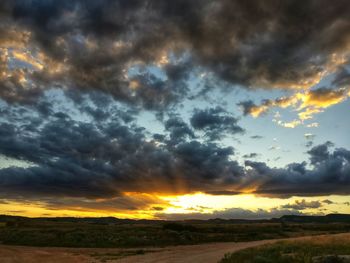 Scenic view of dramatic sky over land during sunset