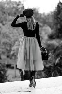 Rear view of woman with umbrella walking outdoors