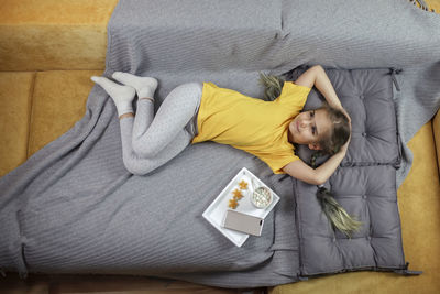 Directly above shot of girl relaxing on sofa at home