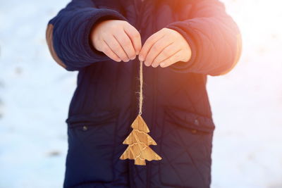 Midsection of child holding wooden christmas tree