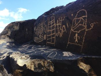 Graffiti on rock formation against sky