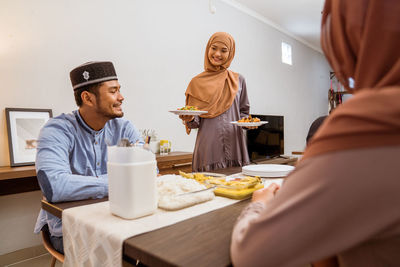 Smiling woman serving food to guest at home