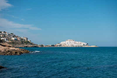 Scenic view of sea by buildings against blue sky