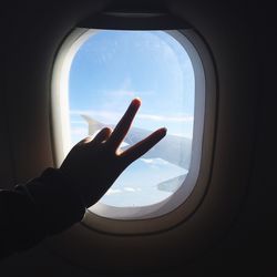 Cropped hand gesturing against airplane window