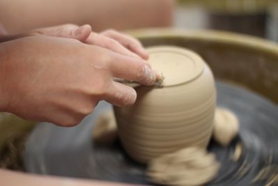 Cropped hands making pottery