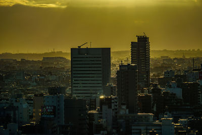 Illuminated cityscape against sky during sunset