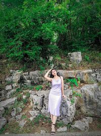 Full length of woman standing by tree in forest