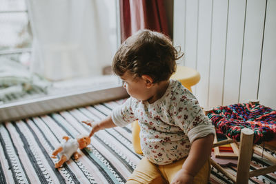 Baby girl playing with toy on bed at home