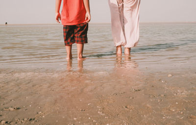 Rear view full length of couple standing at beach