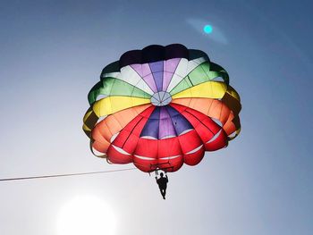 Low angle view of person paragliding against clear sky during sunny day