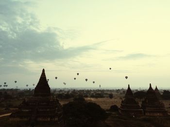 Hot air balloons over stupa temples against sky