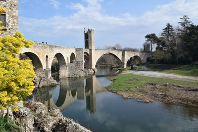 Arch bridge over river against sky