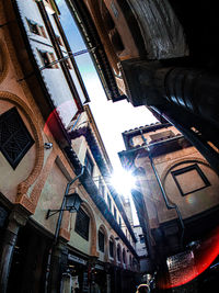 Low angle view of sunlight streaming through buildings