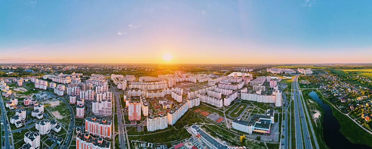 HIGH ANGLE VIEW OF ILLUMINATED BUILDINGS AGAINST SKY DURING SUNSET