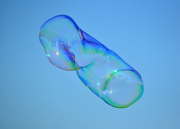 Low angle view of bubble flying against clear blue sky