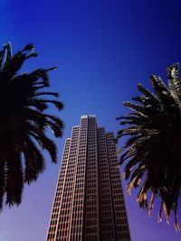 Low angle view of tall building against clear blue sky