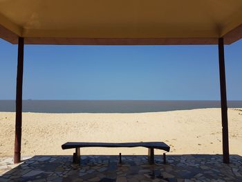 Deck chairs on beach against clear blue sky