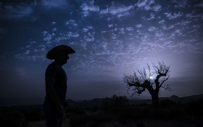 Rear view of woman standing against sky during sunset