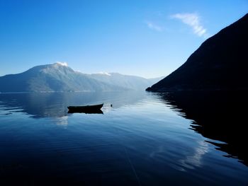 Scenic view of lake and mountains against blue sky