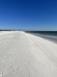 Scenic view of beach against clear blue sky