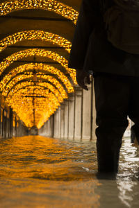 Low section of man standing in illuminated water