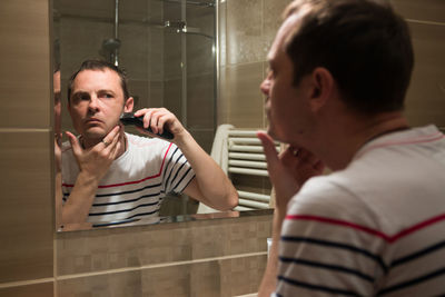 Reflection of man shaving in mirror at home