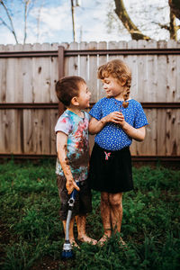 Young brother and sister covered in mud looking at each other