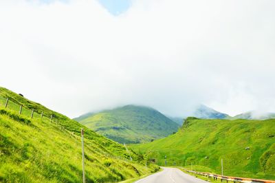 Road amidst green landscape against sky