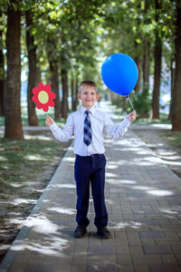 Full length portrait of smiling boy holding balloons