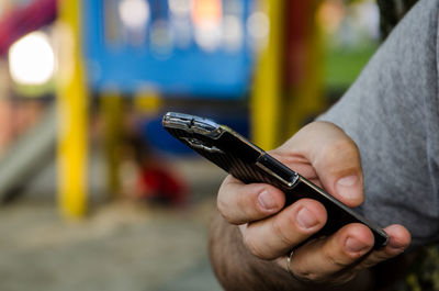 Cropped hand of man using mobile phone in public park