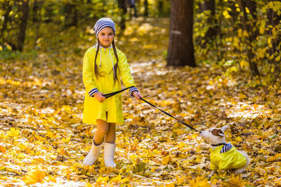 Girl with yellow umbrella in forest during autumn