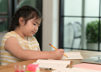 Boy drawing on book at table