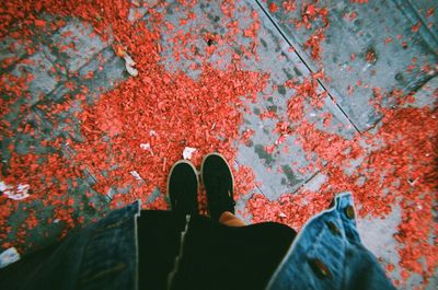 Low section of person standing by red shoes