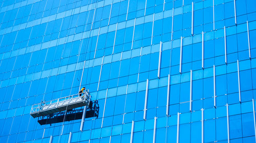 Low angle view of worker cleaning building windows
