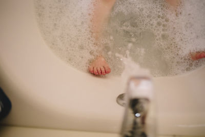 Low section of girl bathing in bathtub