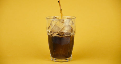 Close-up of drink in glass against yellow background